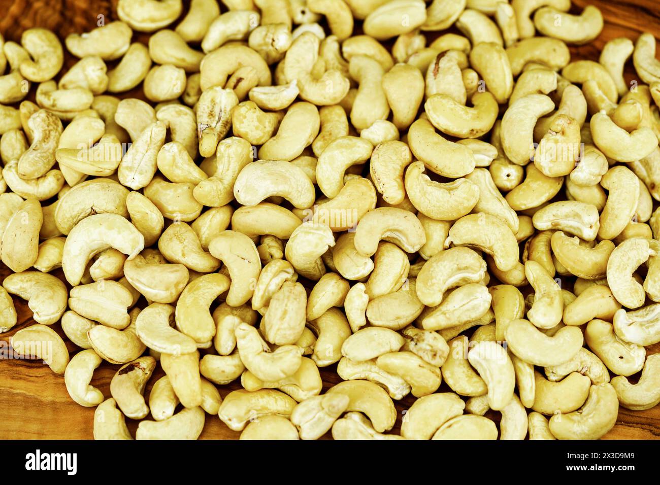 Cashewnüsse (Anacardium occidentale), Cashewnüsse auf einem Holzbrett Stockfoto