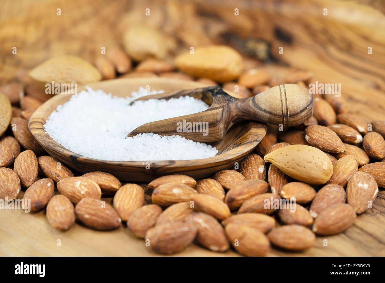 Mandel (Prunus dulcis, Prunus amygdalus, Amygdalus communis, Amygdalus dulcis), gesalzene Mandeln, ungesackte Mandeln und Holzlöffel mit Salz Stockfoto