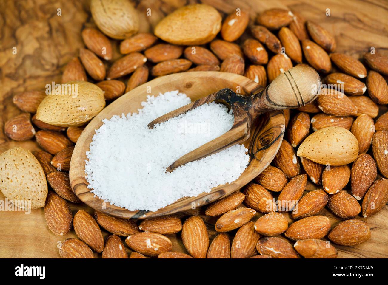 Mandel (Prunus dulcis, Prunus amygdalus, Amygdalus communis, Amygdalus dulcis), gesalzene Mandeln, ungesackte Mandeln und Holzlöffel mit Salz Stockfoto