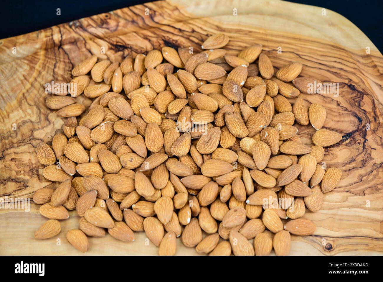 Mandel (Prunus dulcis, Prunus amygdalus, Amygdalus communis, Amygdalus dulcis), rohe Mandeln auf einem Holzbrett Stockfoto