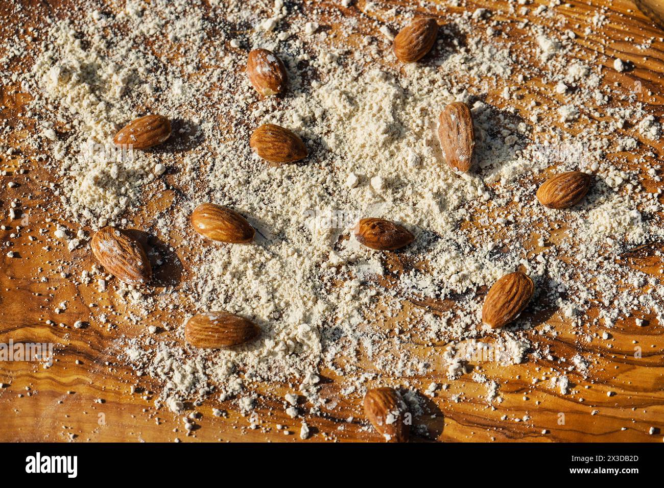 Mandel (Prunus dulcis, Prunus amygdalus, Amygdalus communis, Amygdalus dulcis), rohe und gemahlene Mandeln auf einem Holzbrett Stockfoto