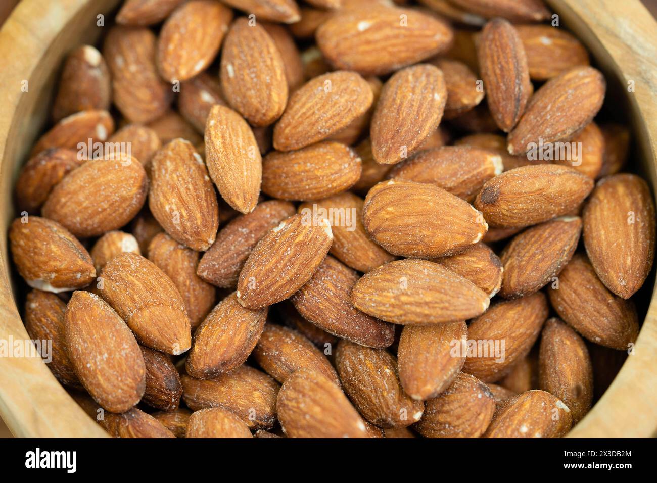 Mandel (Prunus dulcis, Prunus amygdalus, Amygdalus communis, Amygdalus dulcis), gesalzene Mandeln in einer Holzschale Stockfoto