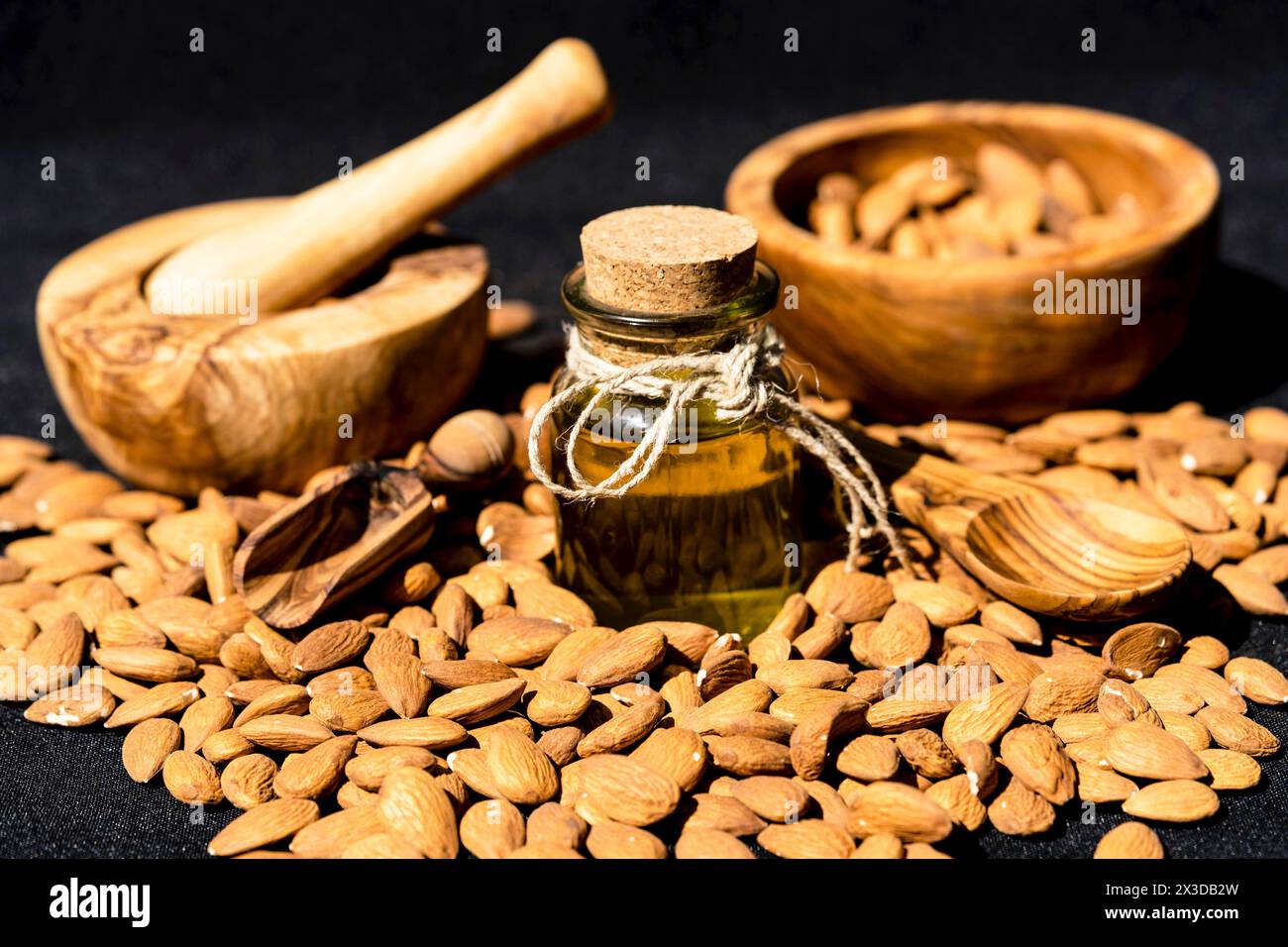 Mandel (Prunus dulcis, Prunus amygdalus, Amygdalus communis, Amygdalus dulcis), rohe Mandeln mit einer Glasflasche Mandelöl, Mörtel und Holzschale Stockfoto