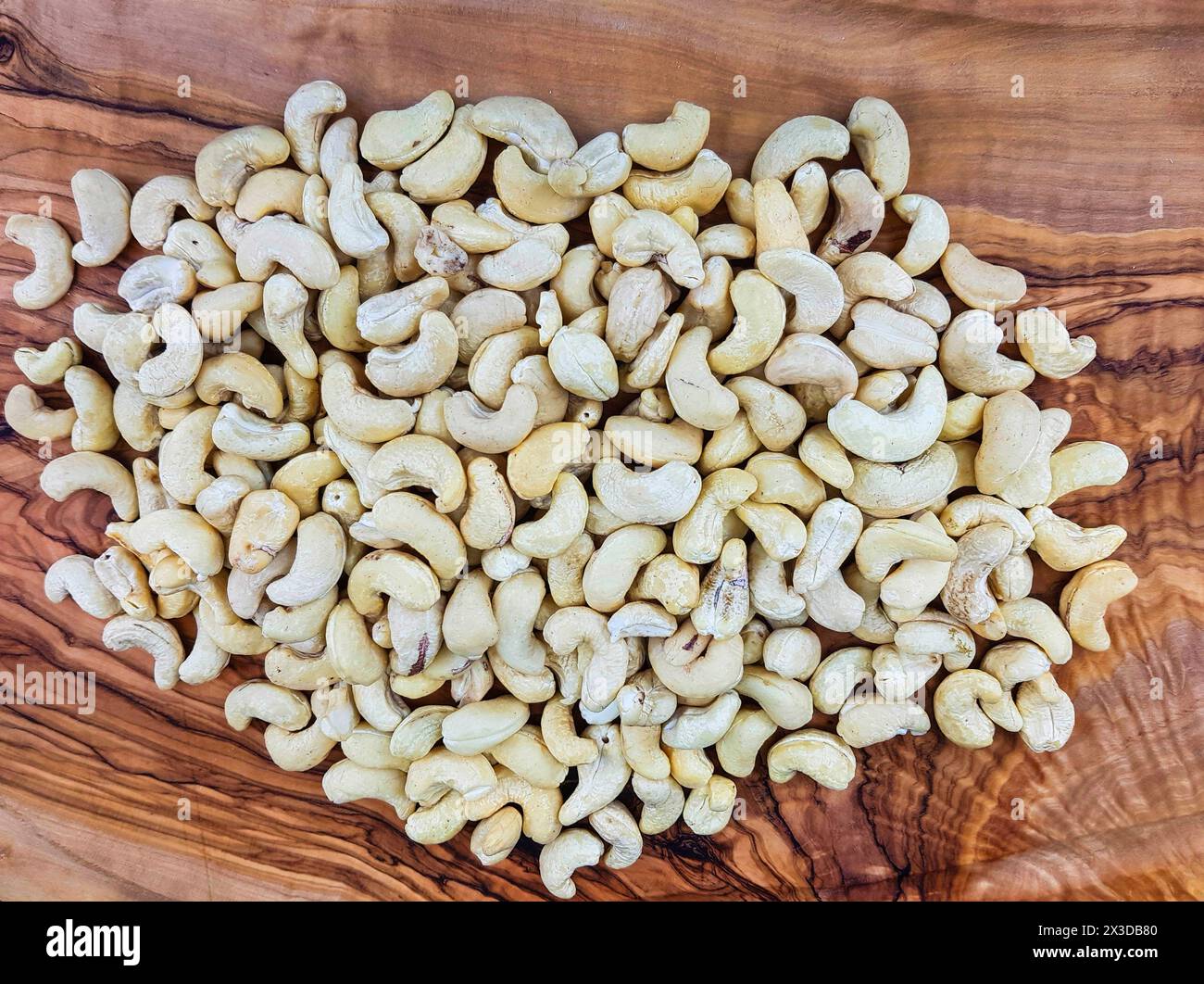 Cashewnüsse (Anacardium occidentale), Cashewnüsse auf einem Holzbrett Stockfoto