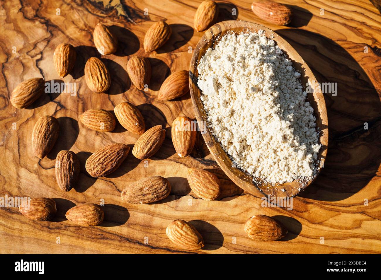Mandel (Prunus dulcis, Prunus amygdalus, Amygdalus communis, Amygdalus dulcis), rohe und gemahlene Mandeln mit einer Holzschale Stockfoto
