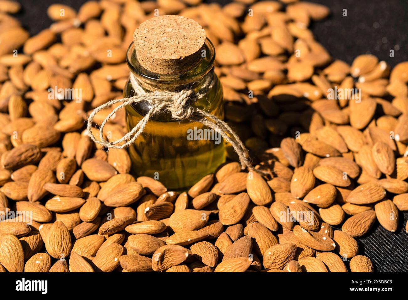 Mandel (Prunus dulcis, Prunus amygdalus, Amygdalus communis, Amygdalus dulcis), rohe Mandeln mit einer Glasflasche Mandelöl Stockfoto