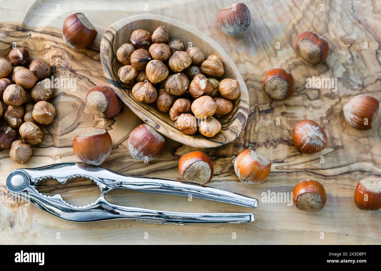 Haselnuss (Corylus avellana), Haselnüsse, ganz und zerrissen, in einer Schüssel, mit Nussknacker Stockfoto