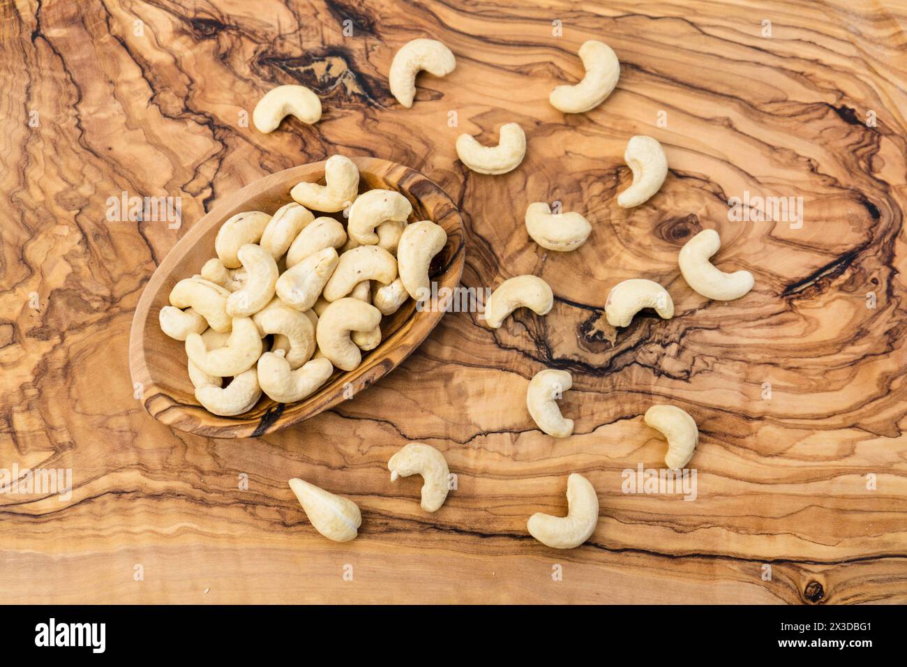 Cashewnüsse (Anacardium occidentale), Cashewnüsse in einer Holzschale auf einem Holztisch Stockfoto