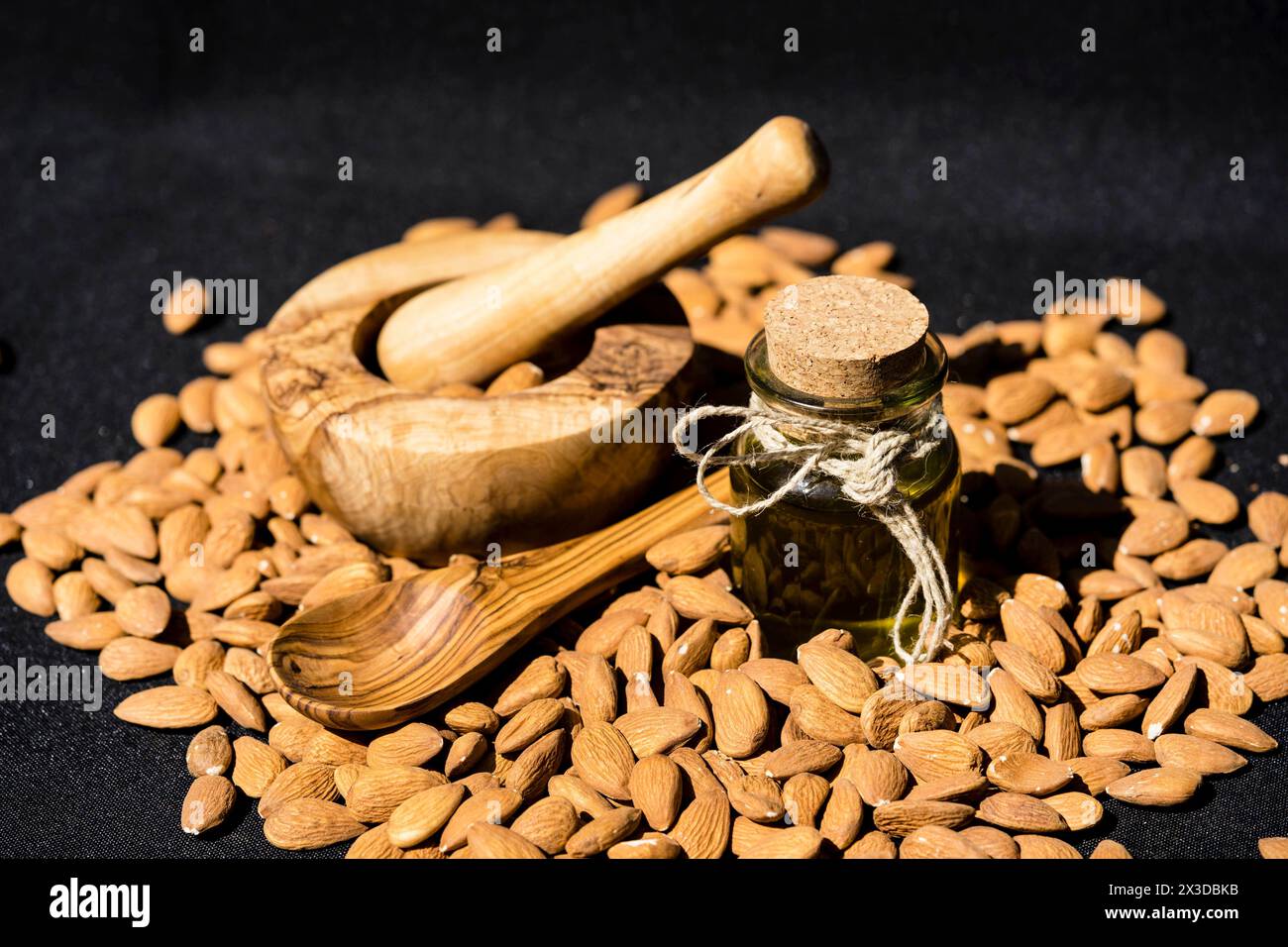 Mandel (Prunus dulcis, Prunus amygdalus, Amygdalus communis, Amygdalus dulcis), rohe Mandeln mit einer Glasflasche Mandelöl, einem Mörtel und einem Holzmörtel Stockfoto