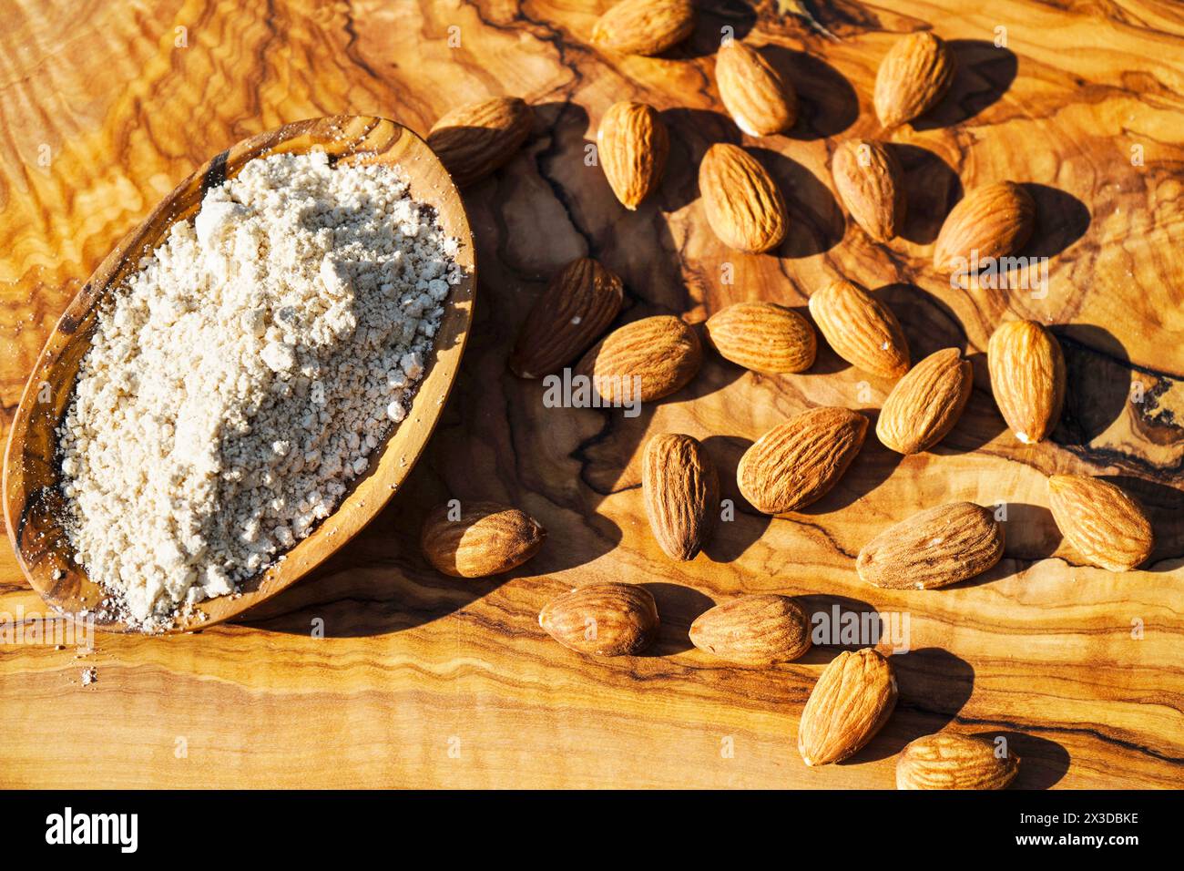 Mandel (Prunus dulcis, Prunus amygdalus, Amygdalus communis, Amygdalus dulcis), rohe und gemahlene Mandeln mit einer Holzschale Stockfoto