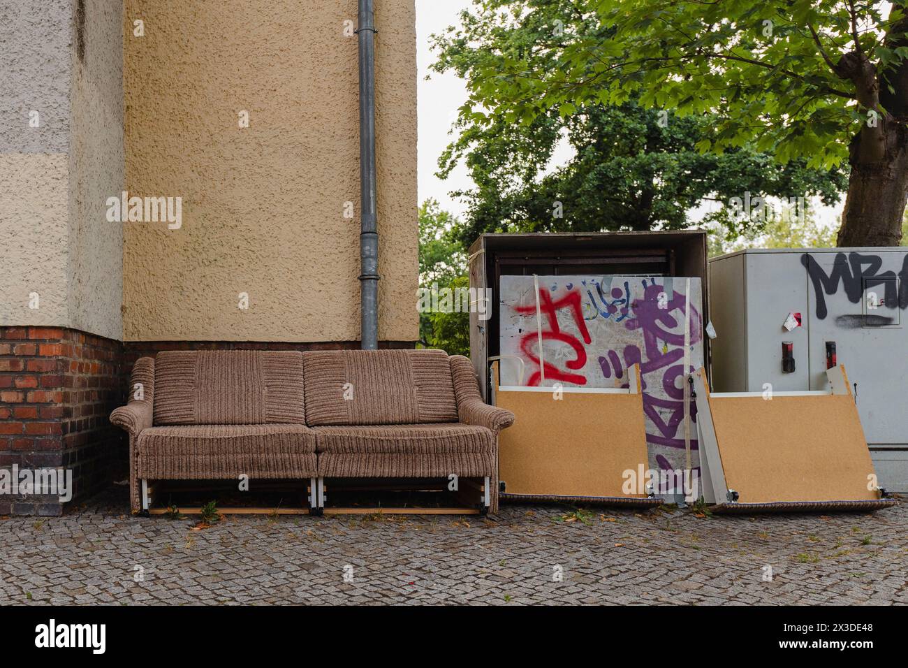 Eine alte Couch auf dem Bürgersteig, sperriger Abfall auf der Straße, sperriger Abfall in der Stadt Stockfoto