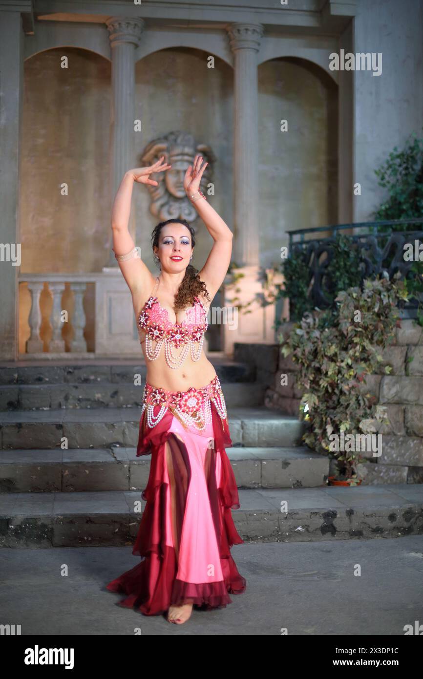 Eine schöne Frau in einem rosa Kleid mit Perlen spielt arabischen Tanz Stockfoto
