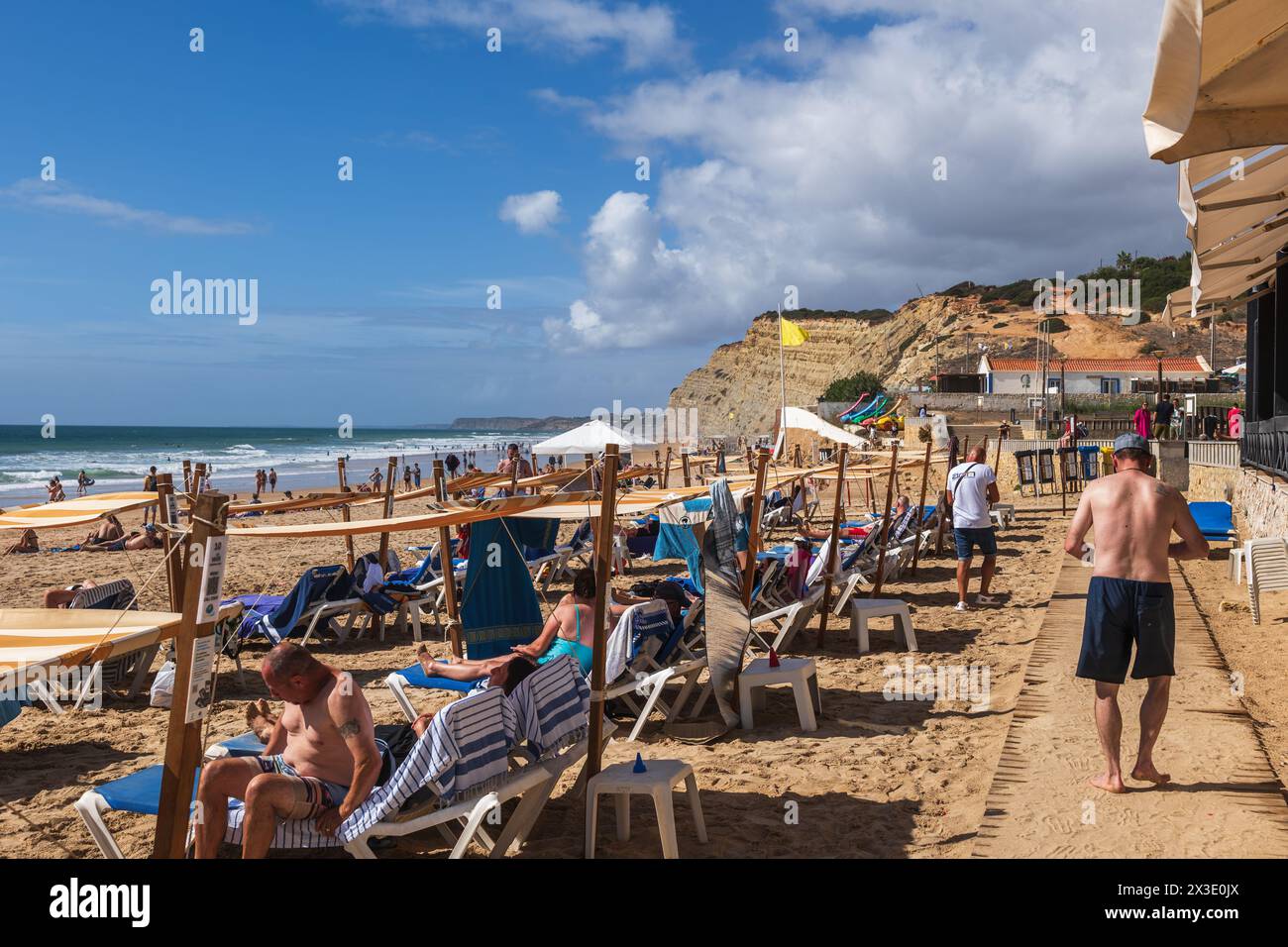 Lagos, Algarve, Portugal, Menschen auf Liegestühlen am Strand Praia de Porto de Mos am Atlantik. Stockfoto