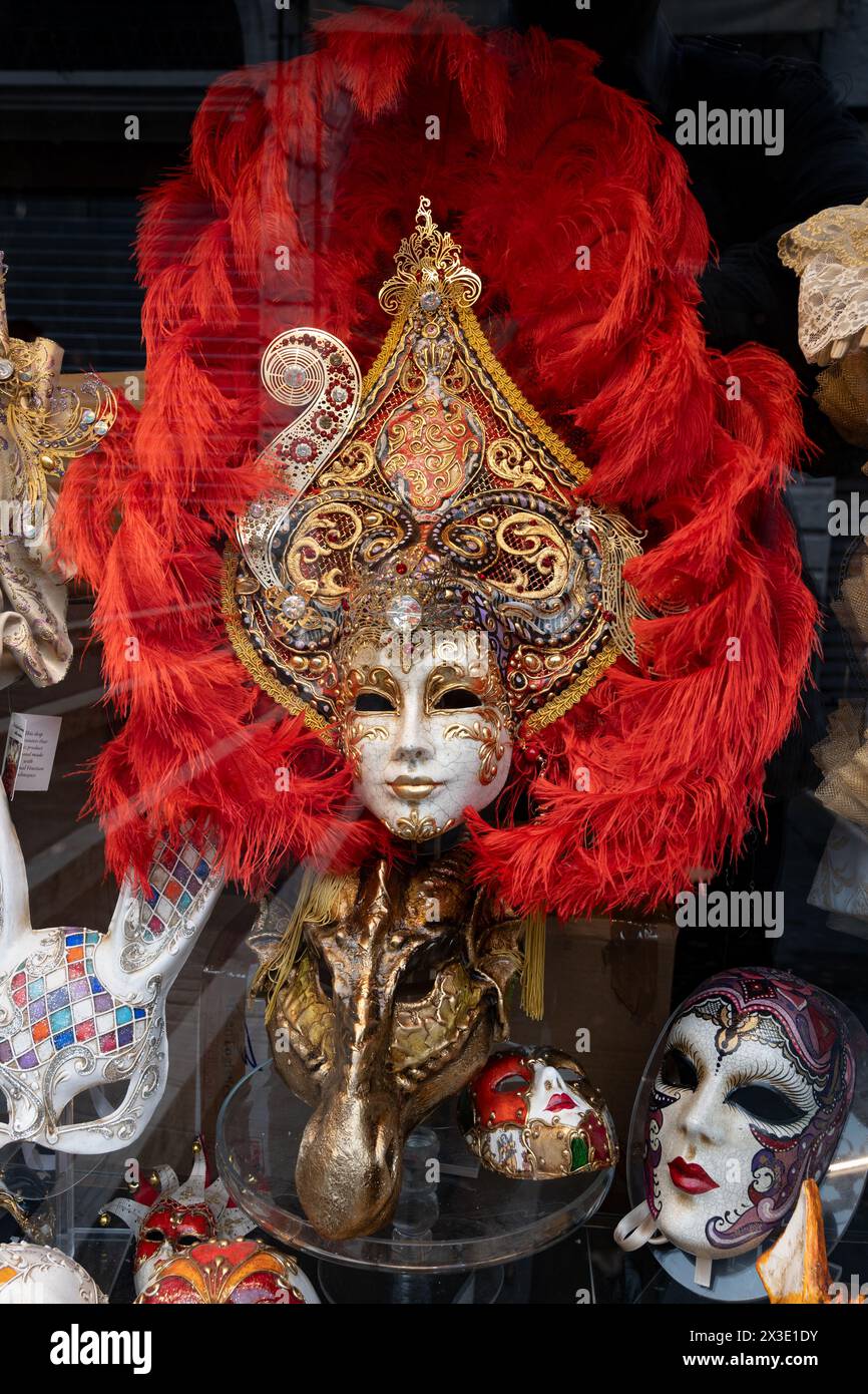Wunderschöne traditionelle venezianische Karnevalsmaske mit roten Federn in Venedig, Italien, authentische und originelle, einzigartige handgefertigte Maske aus Papiermaché i Stockfoto