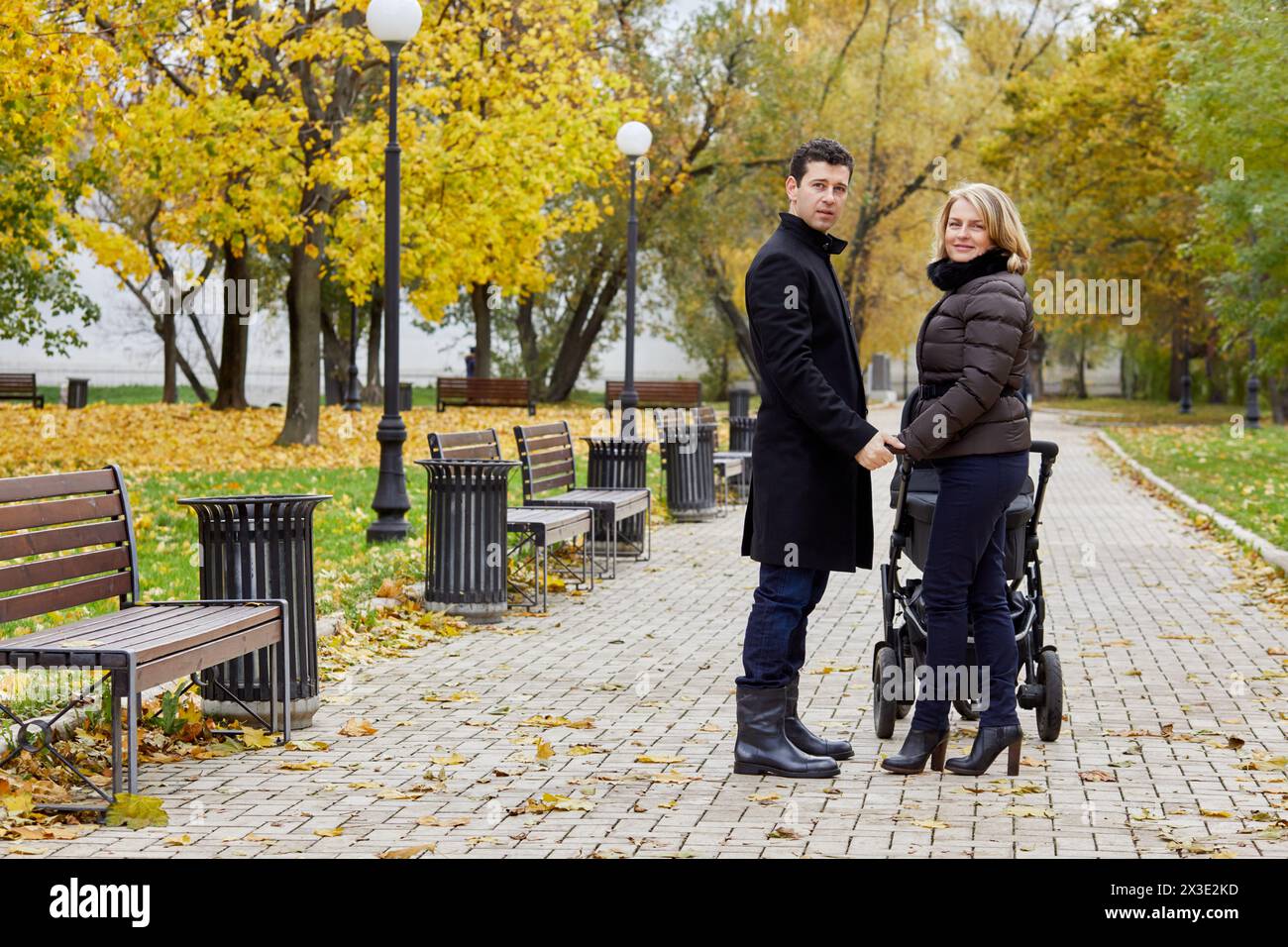 Mann und Frau mit Passiergerät stehen in gleicher Richtung auf dem Weg im Herbstpark. Stockfoto