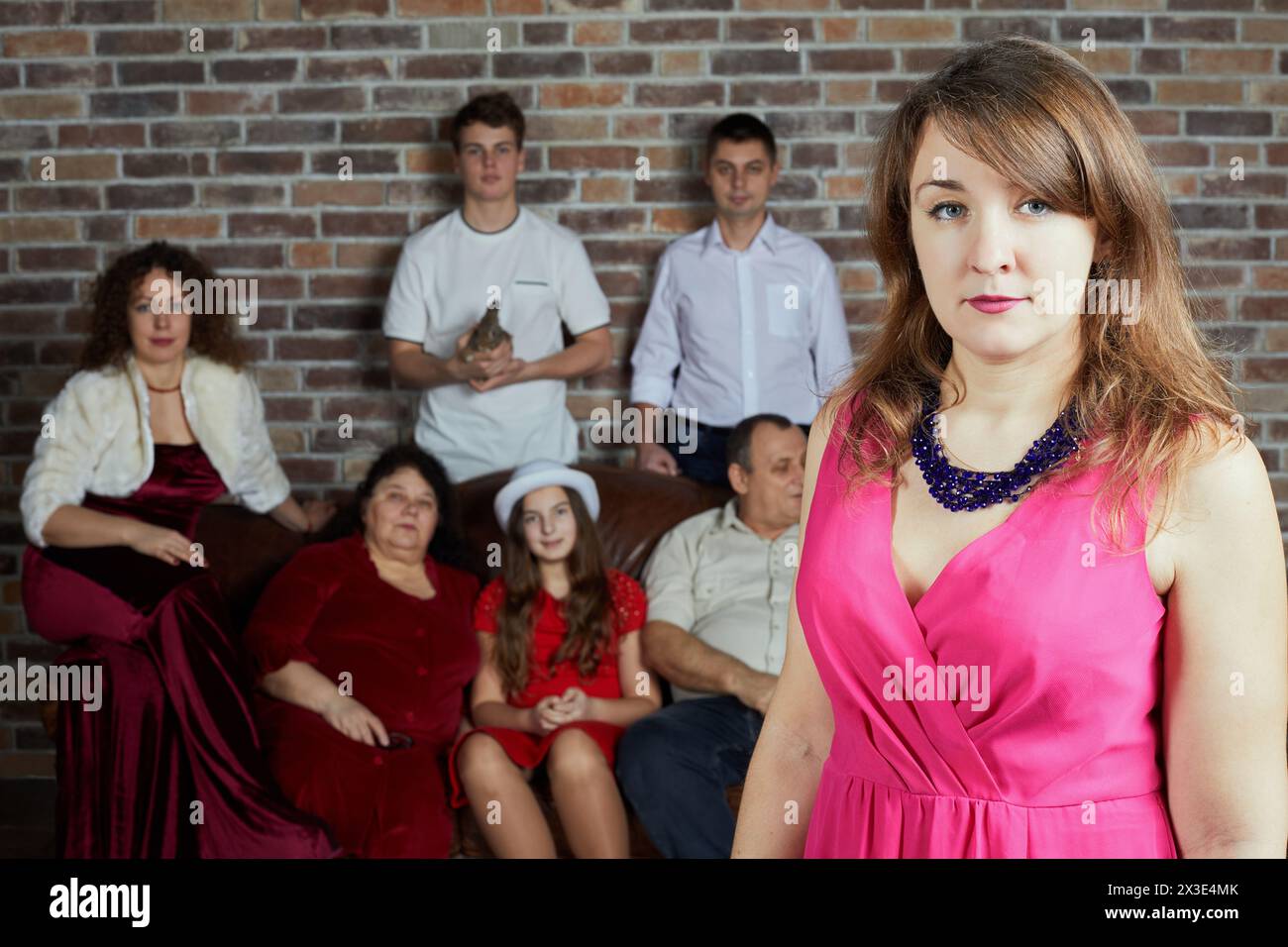 Porträt der Frau gegen die Familie, die im Zimmer auf dem Sofa sitzt. Stockfoto