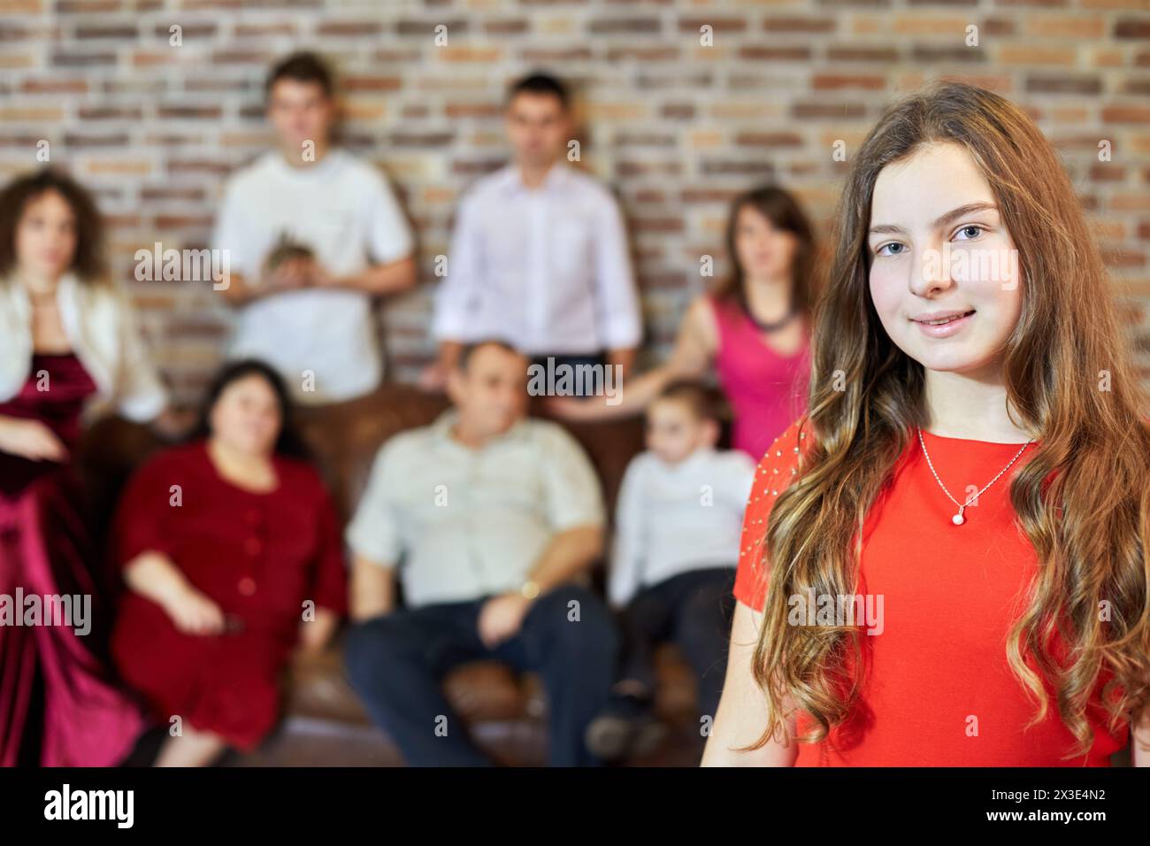 Porträt von Mädchen gegen Familie, die auf Sofa im Zimmer sitzt. Stockfoto