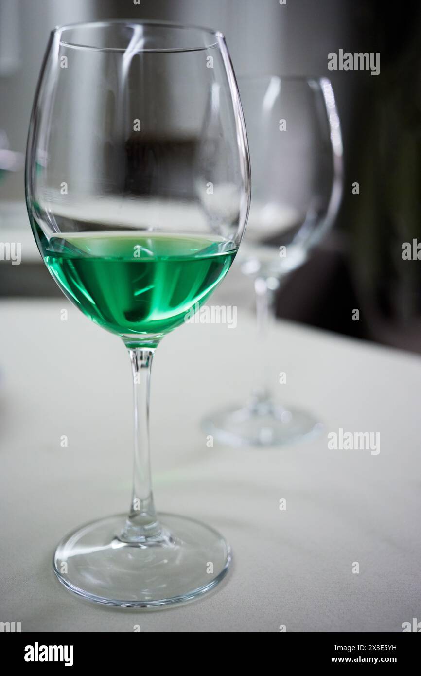 Weinglas mit grünem Getränk und ein weiteres leeres auf dem Tisch im Café. Stockfoto