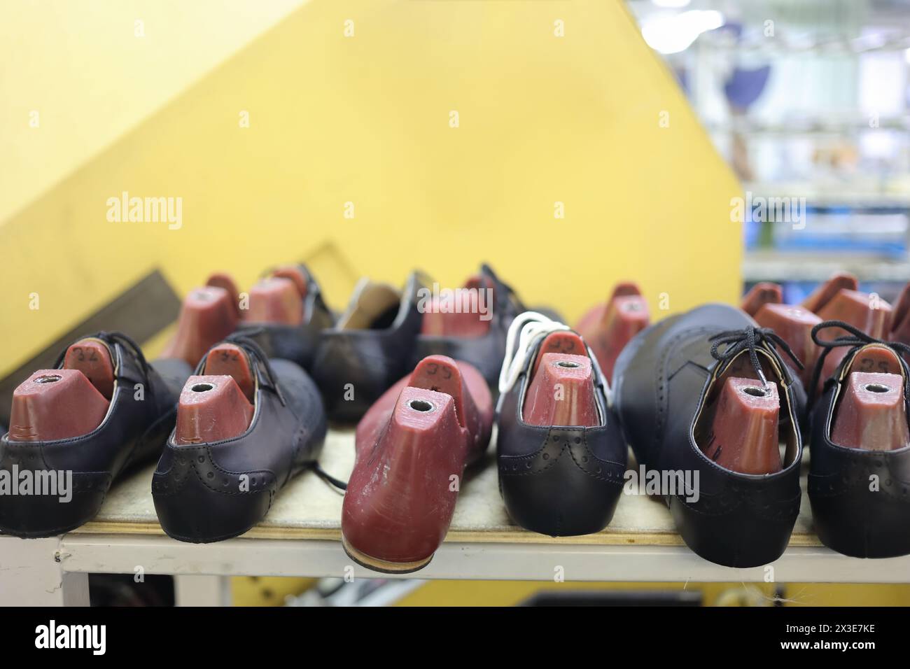 Männliche schwarze Lederschuhe mit Kunststoffschuhen auf dem Regal in der Werkstatt in der Fabrik Stockfoto