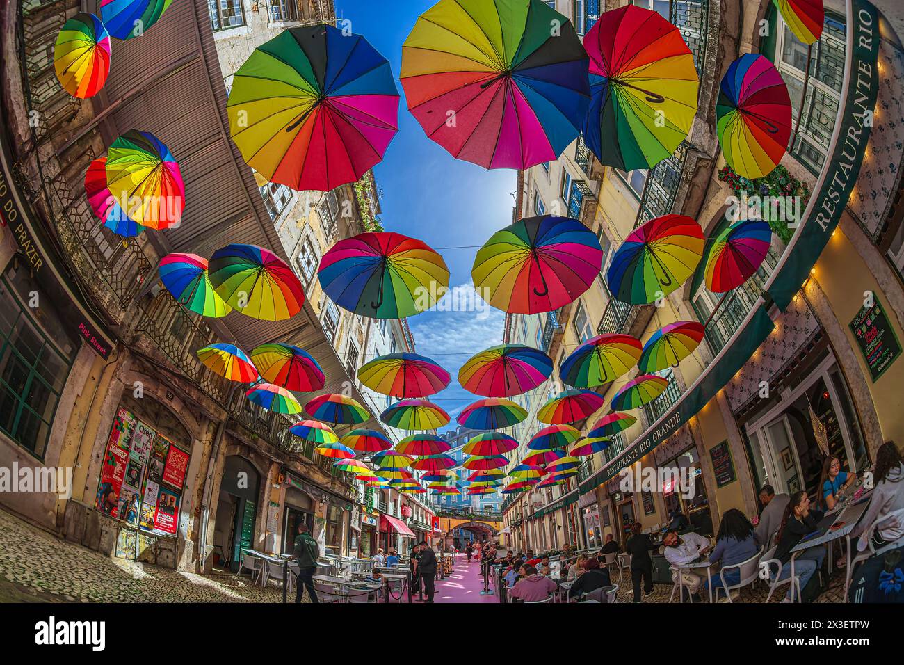 LISSABON, PORTUGAL - 7. APRIL 2024: Die berühmte rosa Fußgängerzone von Rua Nova do Carvalho, Cais do Sodre, mit farbenfrohen Regenschirmen Hangi Stockfoto