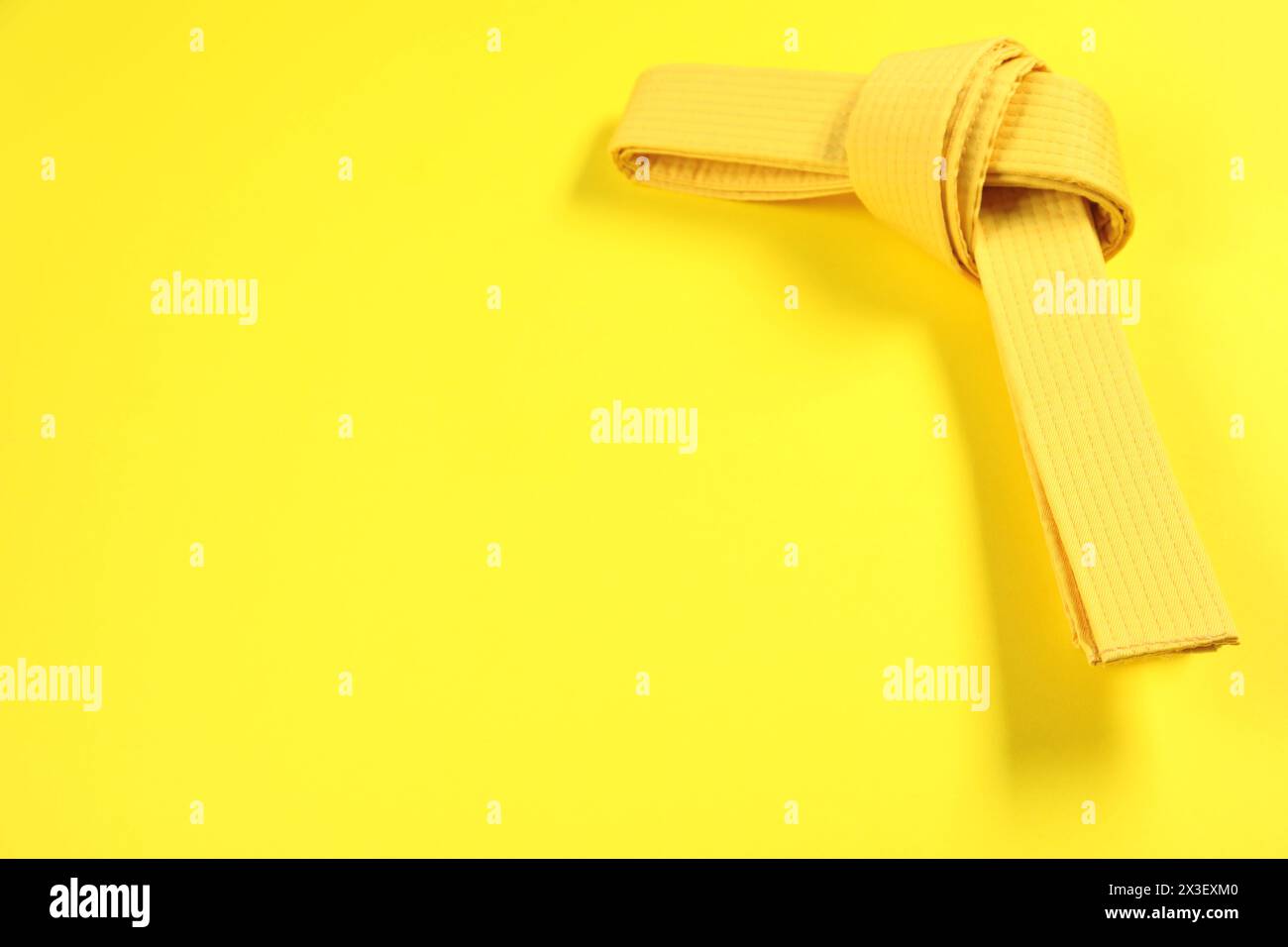 Karate-Gürtel auf gelbem Hintergrund, Platz für Text Stockfoto