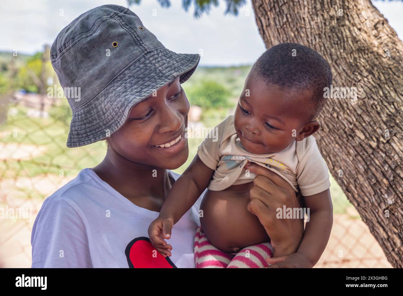 afrikanisches Mädchen im Dorf, das ein Baby hält, ungewollte Schwangerschaft Stockfoto