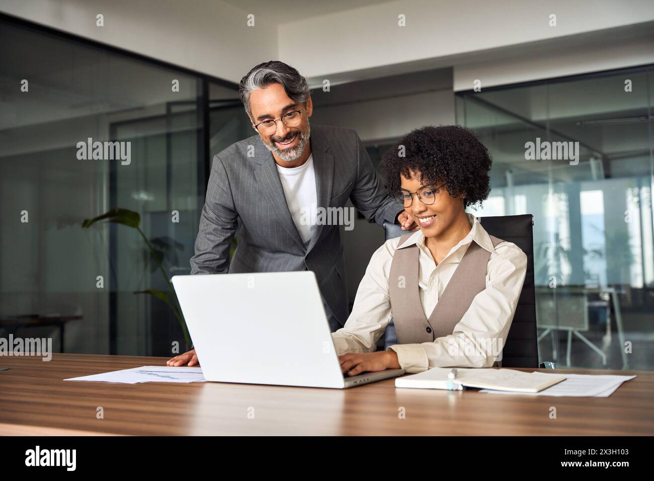 Professionelles Happy Manager Training, das weiblichen Mitarbeitern bei der Computerarbeit hilft. Stockfoto