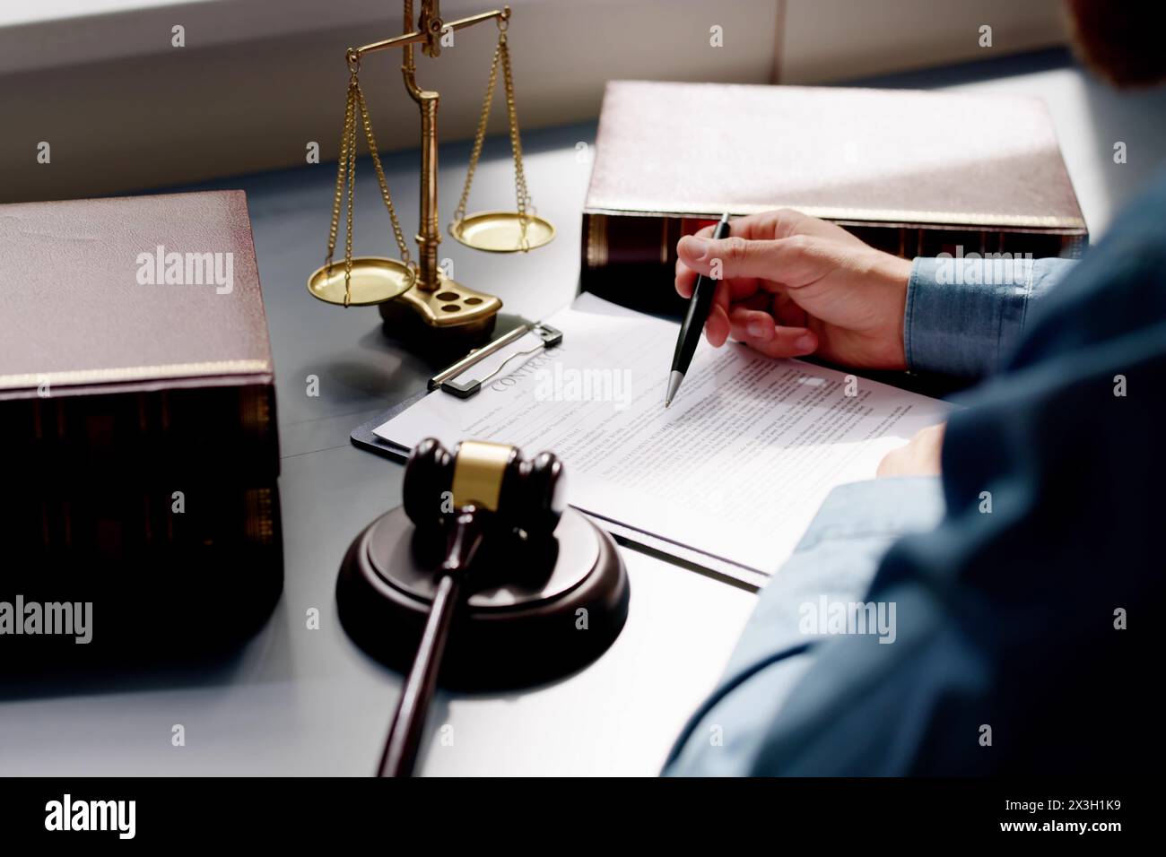 Close-up des Richters Holding Dokument mit Hammer am Schreibtisch Stockfoto
