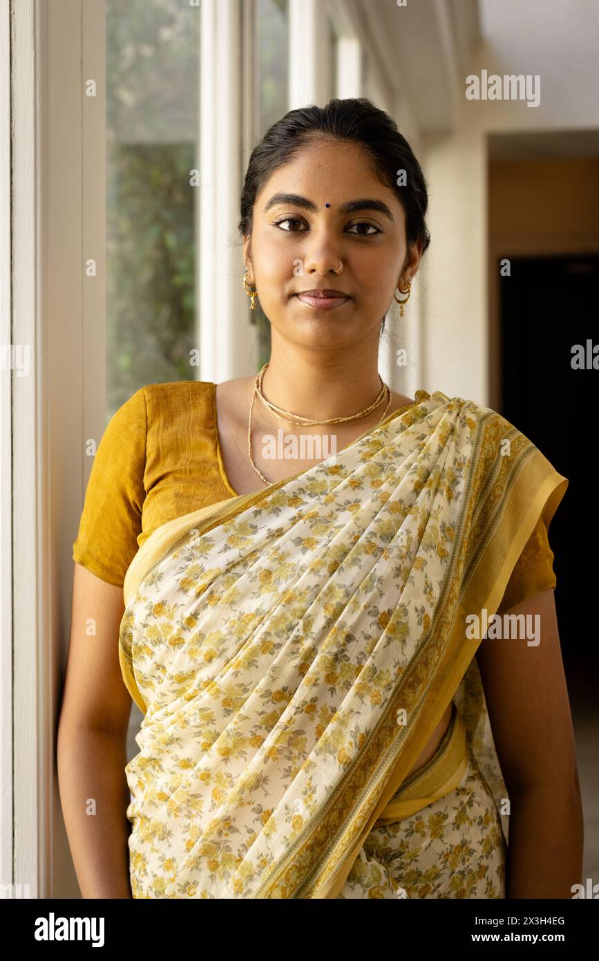 Indische junge Frau mit traditionellem Saree, die zu Hause steht Stockfoto
