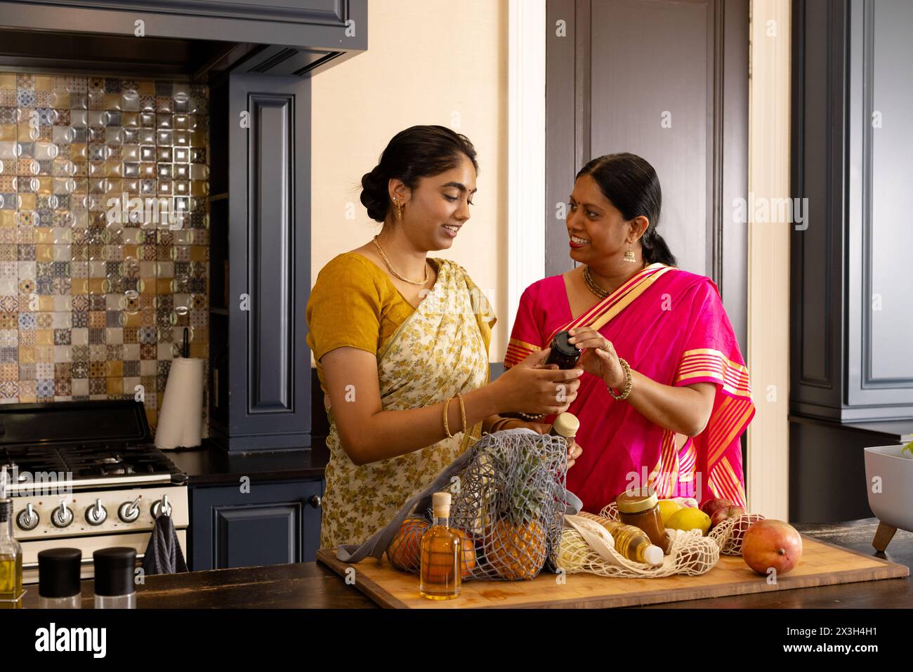 Indische Mutter und Teenager-Tochter in traditioneller Kleidung zu Hause kochen Stockfoto