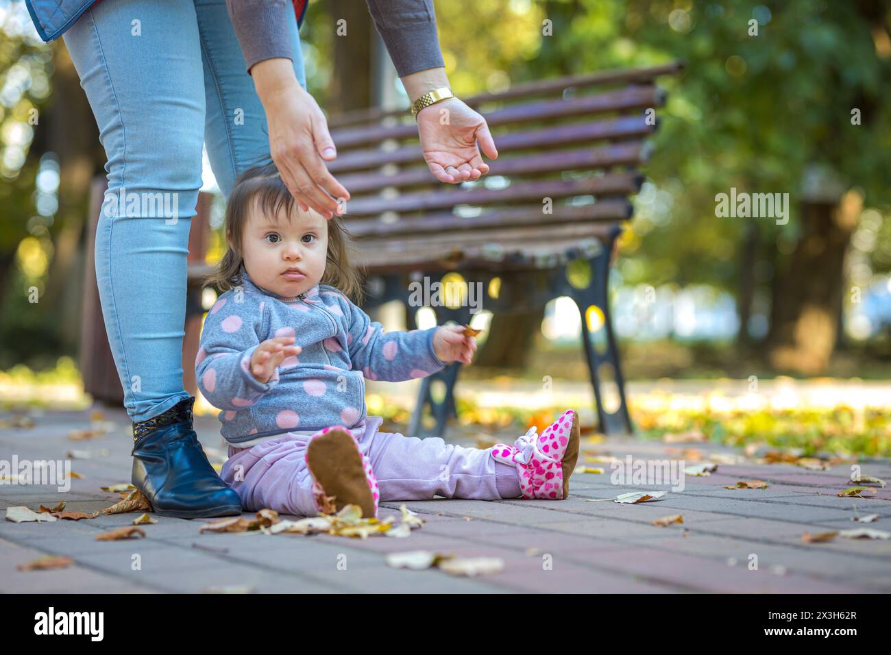 Baby Mädchen, das sich im Park niederlegt und die Hände hebt, um angehoben zu werden Stockfoto