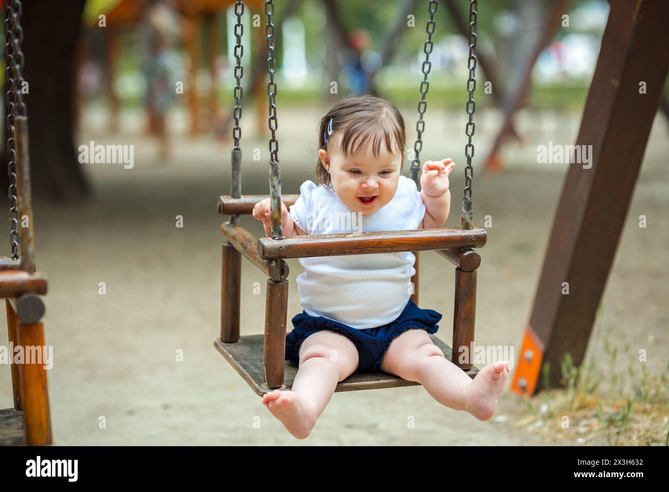 Kleines Mädchen, das in der Wiege im Park schwingt Stockfoto