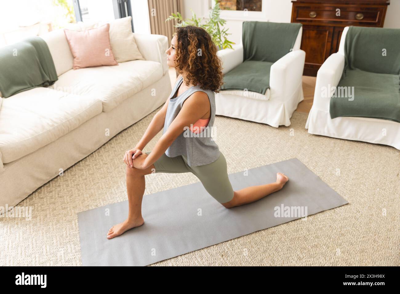 Eine junge kaukasische Frau, die zu Hause Yoga praktiziert Stockfoto