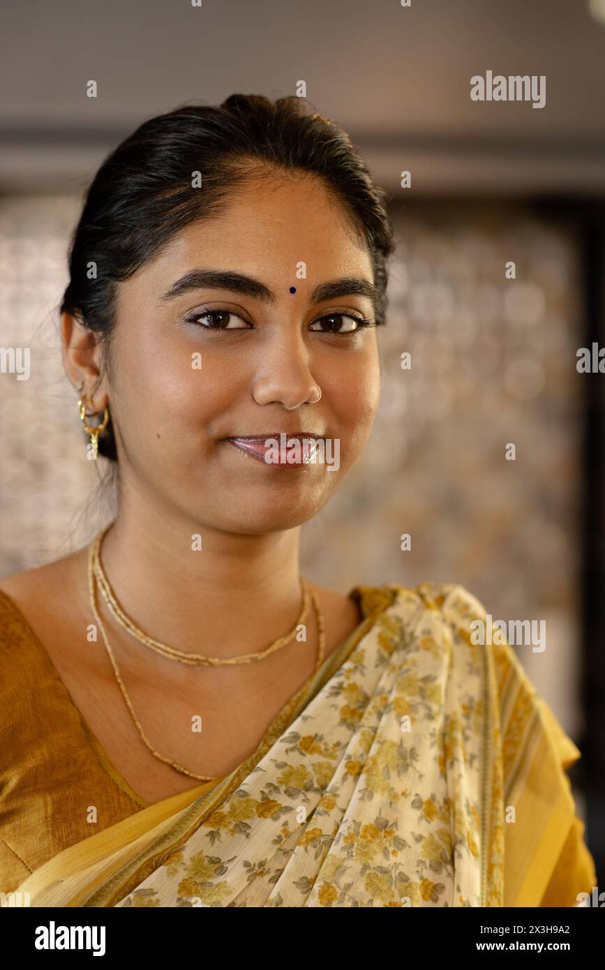 Eine junge indische Frau trägt traditionellen Saree und lächelt zu Hause in die Kamera Stockfoto