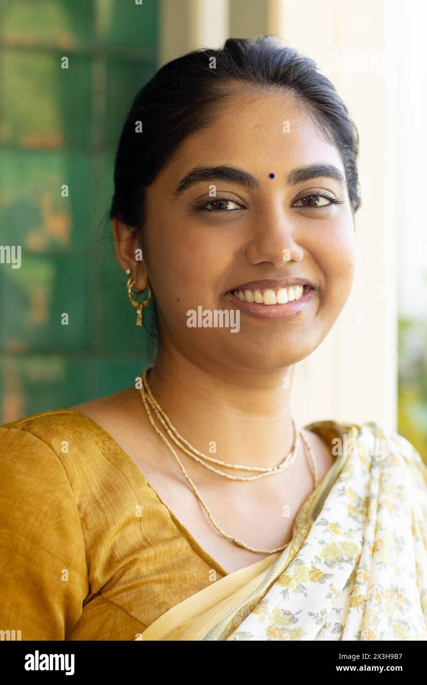 Eine junge indische Frau trägt traditionellen Saree und lächelt zu Hause in die Kamera Stockfoto