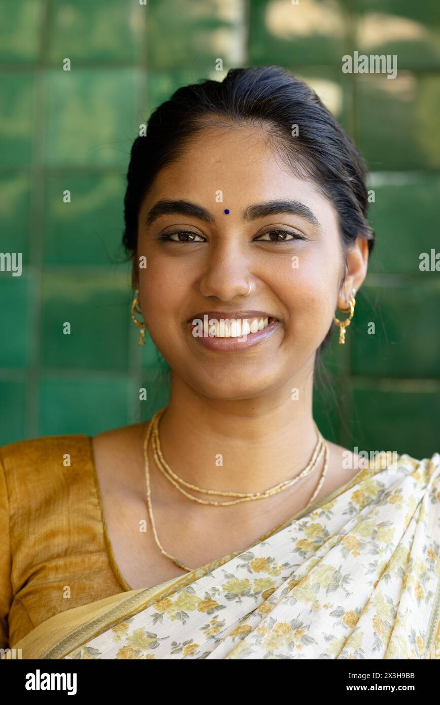 Eine junge indische Frau trägt traditionellen Saree und lächelt zu Hause Stockfoto