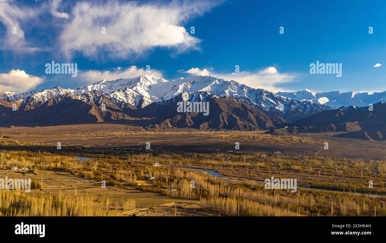 Panoramablick auf das Ladakh-Tal mit blauem Indus-Fluss in der Mitte und schneebedeckten Berggipfeln im Hintergrund. Stockfoto
