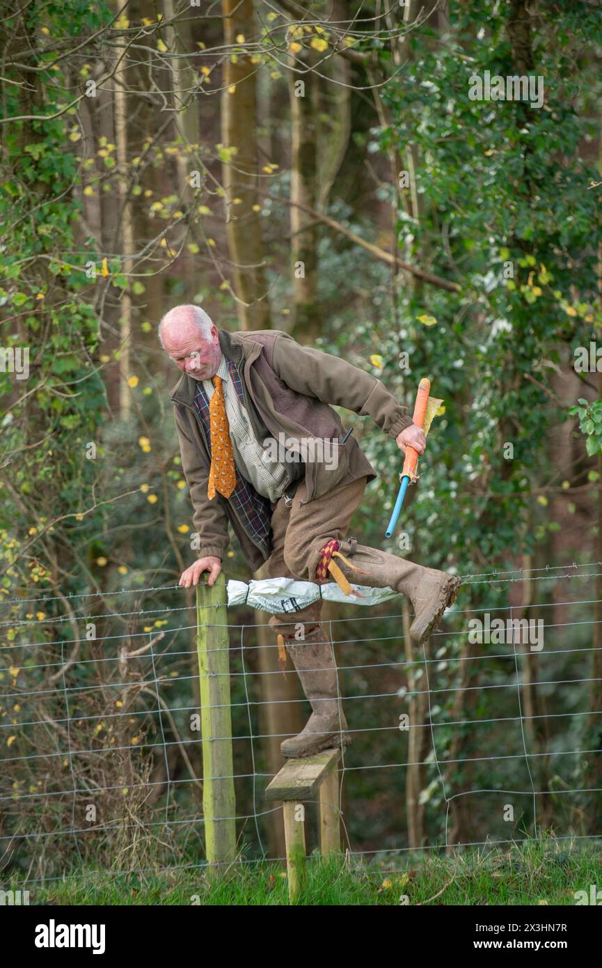 Schläger auf einem Fasanenschuss, der einen Stilzaun überquert Stockfoto