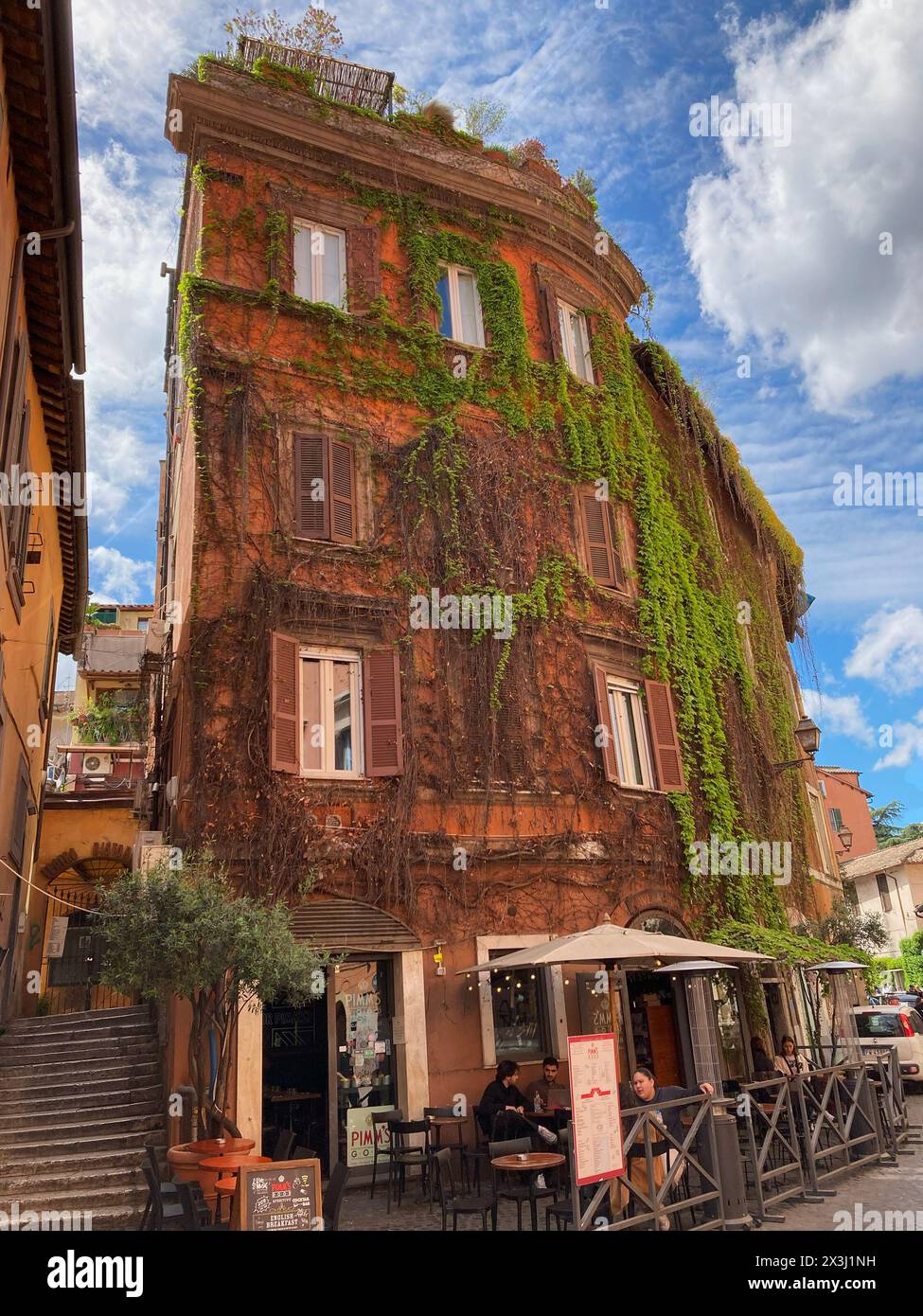 Italien, Rom - 03. April 2024: Altes Gebäude mit Bar im Erdgeschoss in Trastevere, mit Efeu bedeckt Stockfoto