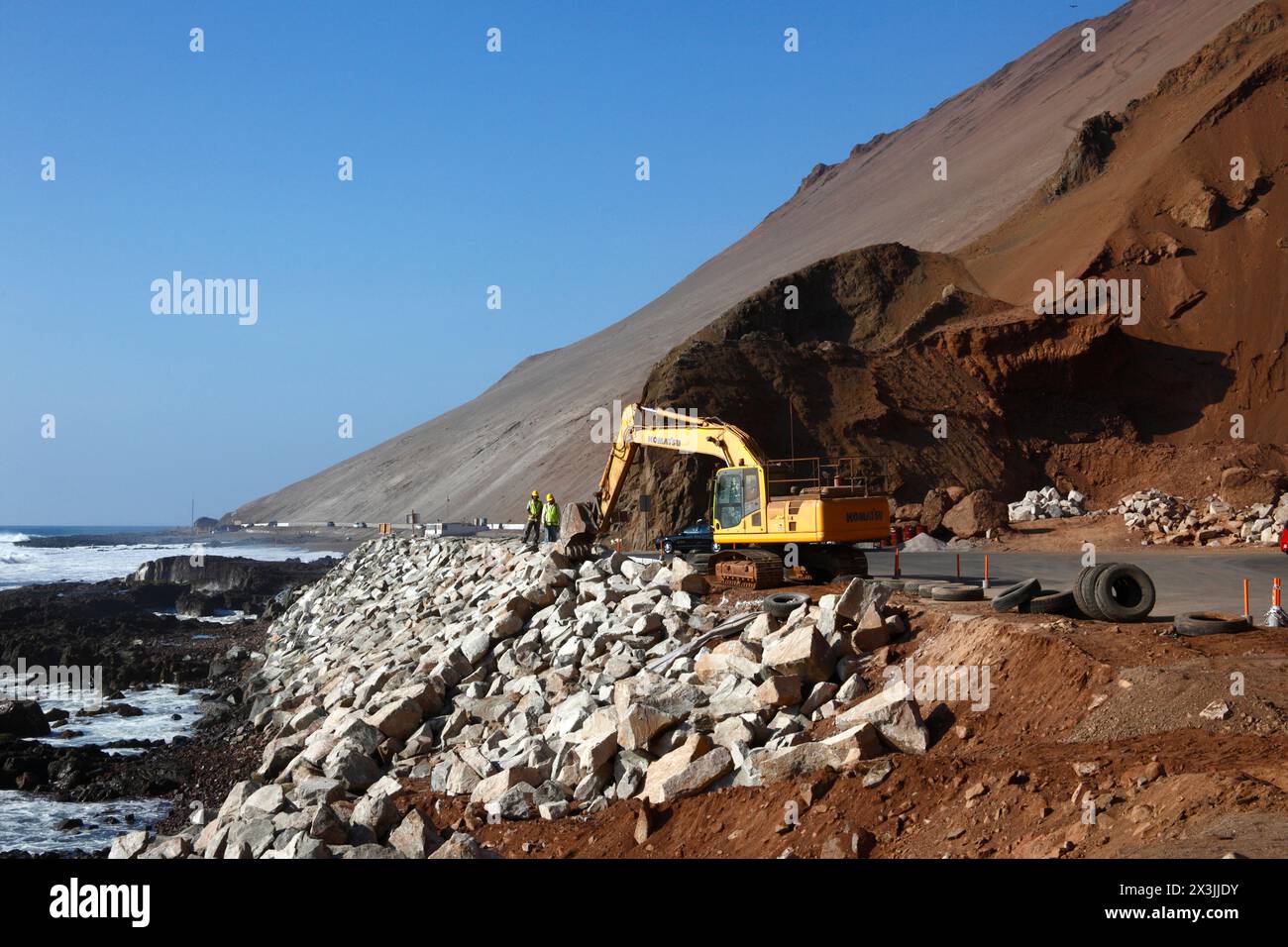 Ein Komatsu-Bagger, der an einem Projekt zur Verbesserung der Straßenzufahrt und der Parkmöglichkeiten für die Cuevas de Anzota/Anzota-Höhlen in der Nähe von Arica, Chile, arbeitet Stockfoto