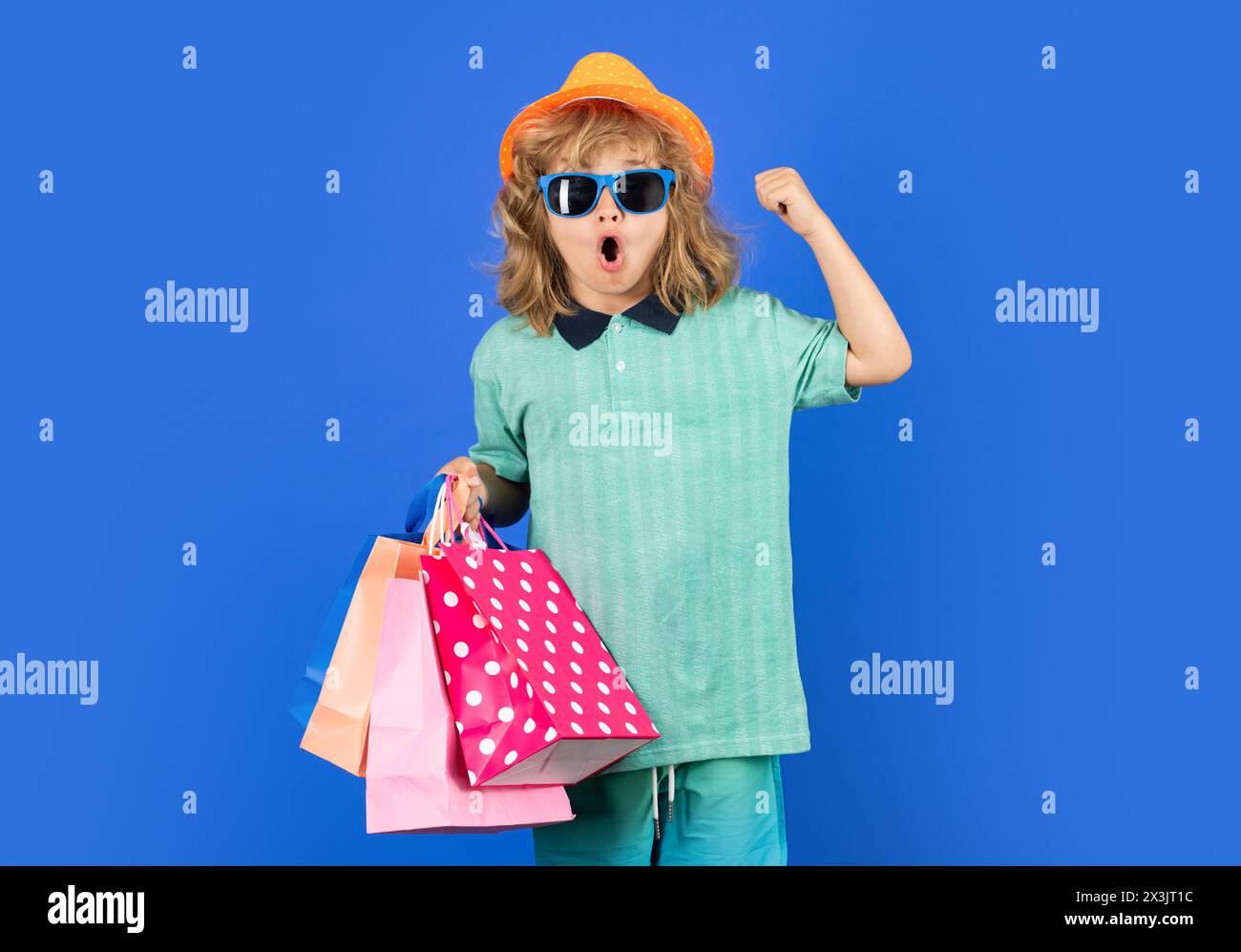 Rabatte und Verkäufe. Glücklicher Junge mit Einkaufstaschen. Junge mit Einkaufstaschen posiert auf blauem Studio isoliertem Hintergrund. Trends und Marken Stockfoto