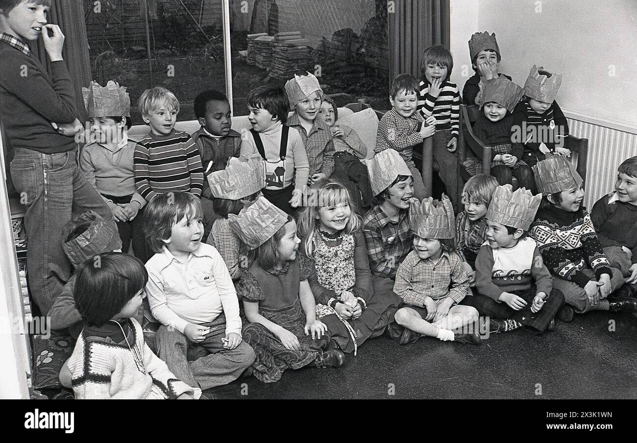 1970er Jahre, Kinderparty, eine Gruppe kleiner Kinder mit Partyhüten, die Spaß haben, versammelten sich in einem Wohnzimmer. Stockfoto