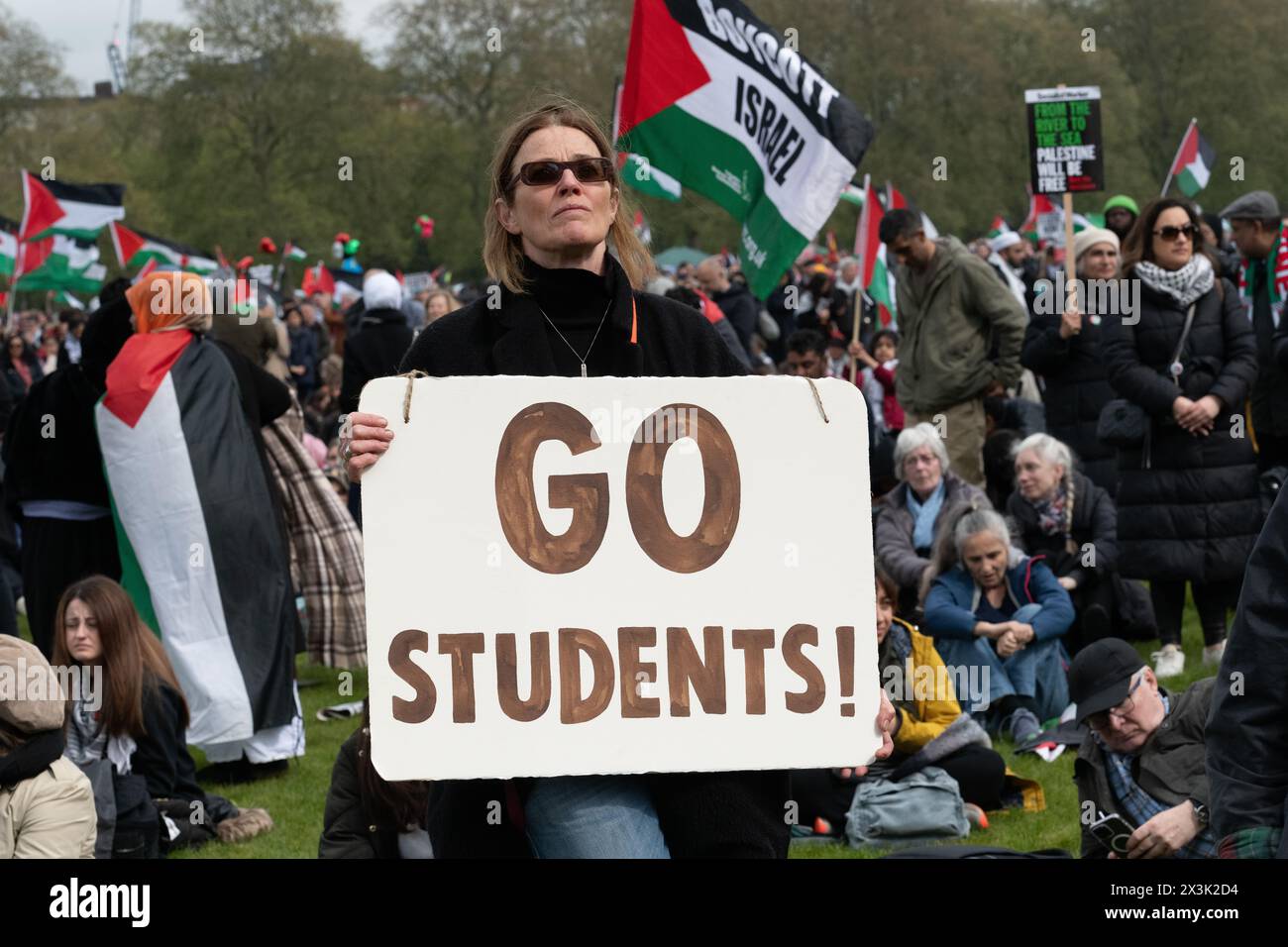 London, Großbritannien. April 2024. Eine Frau hält ein Plakat mit der Aufschrift "gehe zu Studenten!" - Ein Verweis auf streng polizeiliche Studentenproteste in den USA - während sich eine große Menge palästinensischer Unterstützer in Hyde Park versammeln, die einen Waffenstillstand und ein Ende der Unterstützung Großbritanniens und der USA für Israels Belagerung, Bombardierung und Invasion von Gaza nach einem Angriff von Hamas-Militanten fordern. Der Protest war der dreizehnte nationale marsch gegen Israels Krieg gegen Gaza, der im Oktober 2023 begann und vom Holocaust-Gelehrten Raz Segal als „Lehrbuchfall des Völkermords“ beschrieben wurde. Quelle: Ron Fassbender/Alamy Live News Stockfoto