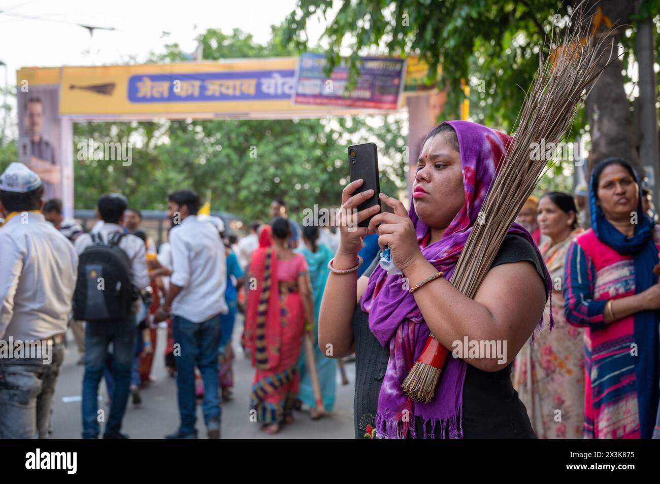 Neu-Delhi, Indien. April 2024. Eine weibliche Unterstützerin der AAM-Aadmi-Partei hält das Symbol der Partei, einen Besen, während sie an einer Roadshow unter der Leitung von Arvind Kejriwals Frau Sunita Kejriwal in Kalyan Puri im Wahlkreis Ost-Delhi teilnimmt. Die AAM Aadmi Party (AAP) führt eine Roadshow vor den Wahlen in Lok Sabha durch. Die AAM Aadmi Party ist eine politische Partei in Indien und derzeit die Regierungspartei im indischen Staat Punjab und im unionsgebiet Delhi. Quelle: SOPA Images Limited/Alamy Live News Stockfoto
