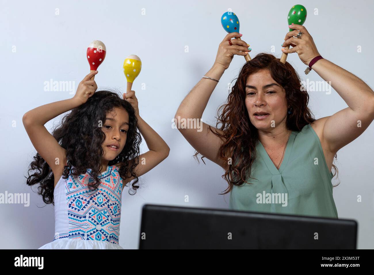 Lateinamerikanische Mutter und Tochter geben virtuellen Musikunterricht mit Schlaginstrumenten Stockfoto