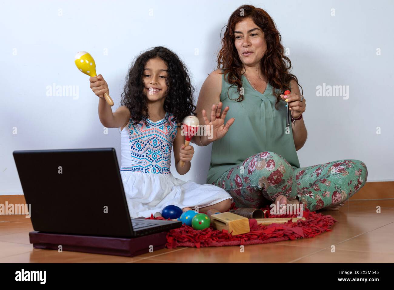 Lateinamerikanische Mutter und Tochter geben virtuellen Musikunterricht mit Schlaginstrumenten Stockfoto