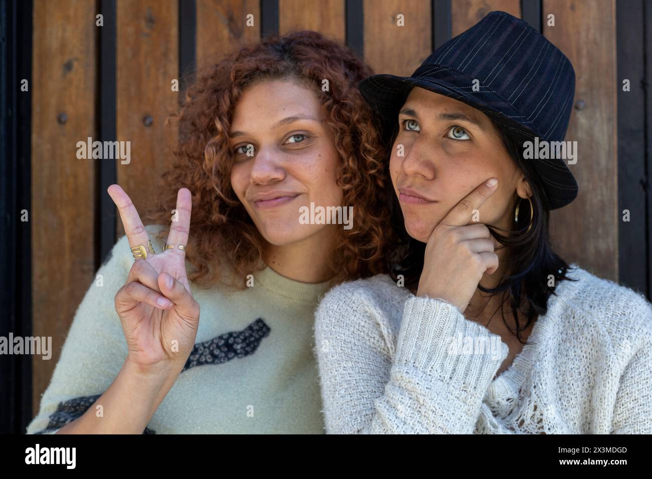 Zwei Erwachsene lateinamerikanische Frauen (34 und 29) mit grünen Augen, eine macht das Friedenszeichen und die andere eine Geste des Denkens, beide haben eine schöne Zeit. Lif Stockfoto