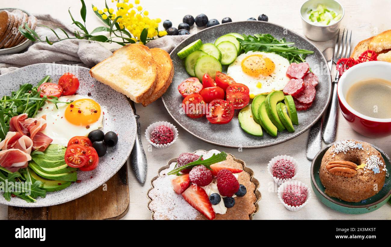 Frühstück mit Kaffee, frischer Bäckerei, Eiern, Salat, Fleisch und Obst. Urlaubskonzept. Draufsicht. Stockfoto