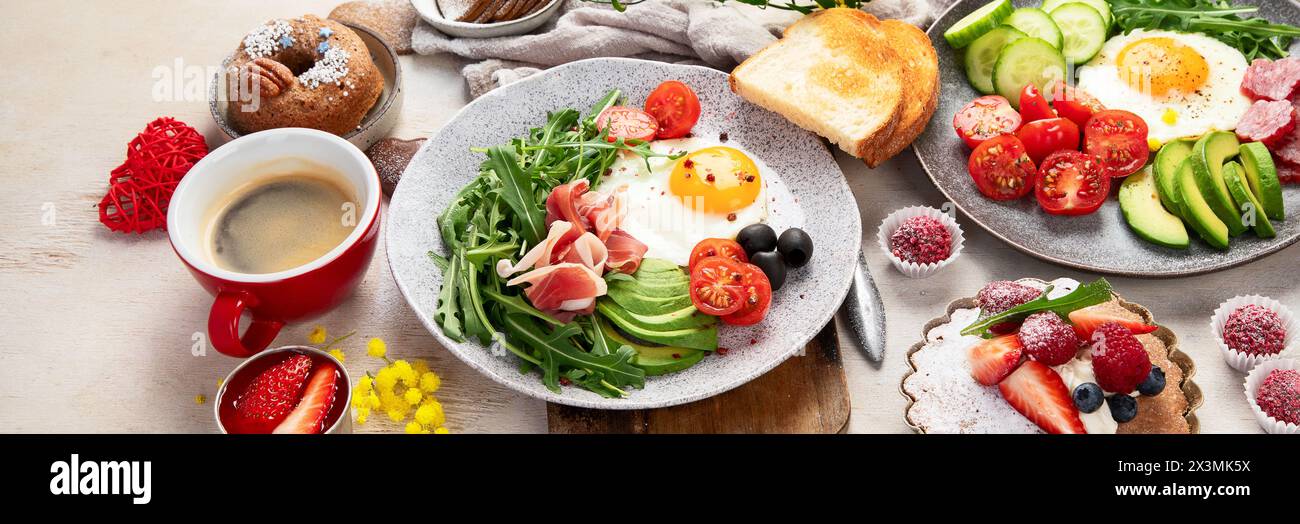 Frühstück mit Kaffee, frischer Bäckerei, Eiern, Salat, Fleisch und Obst. Urlaubskonzept. Draufsicht. Panorama mit Kopierbereich. Stockfoto
