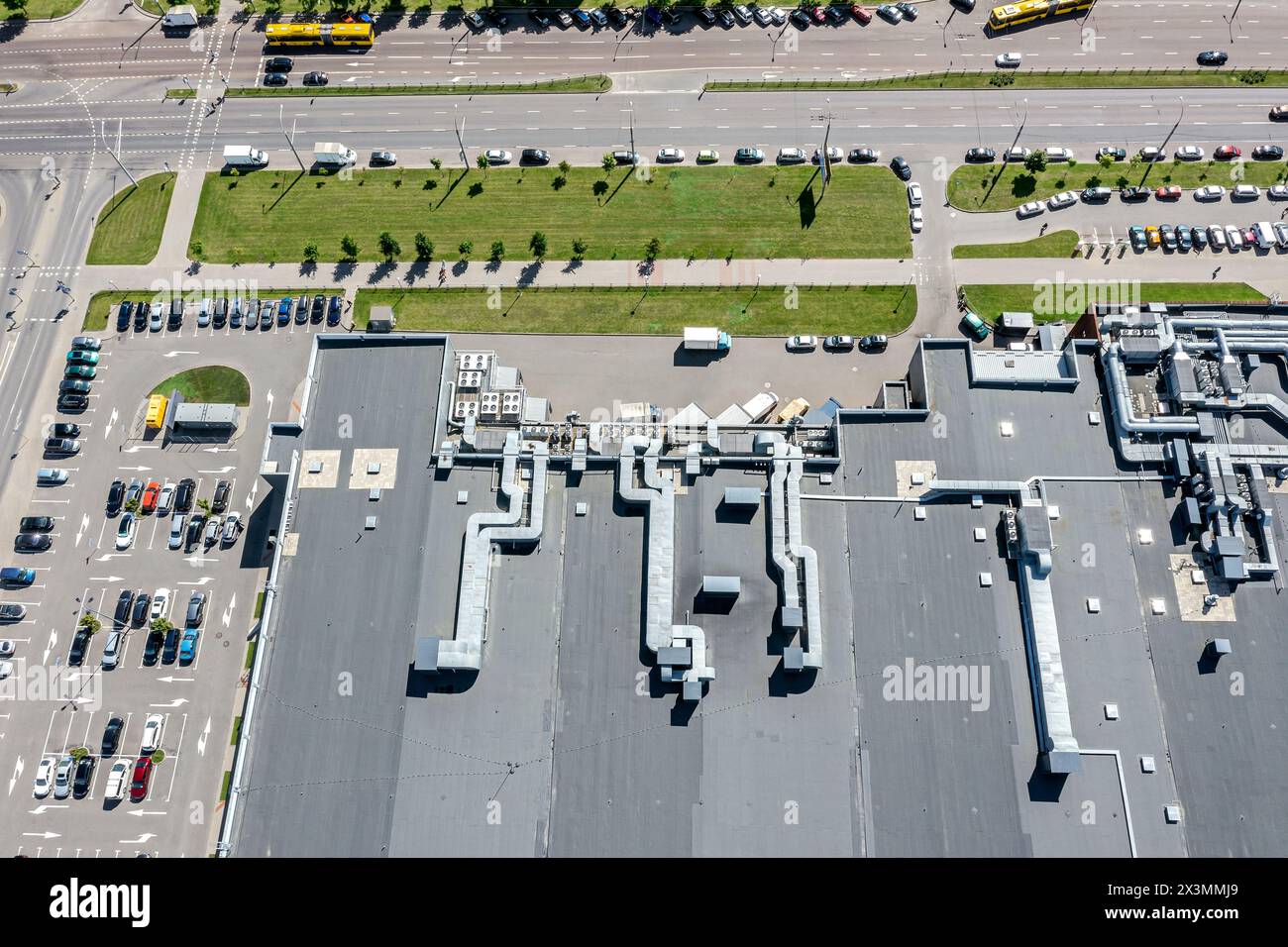 Luftansicht auf das Schindeldach des Einkaufszentrums mit Lüftungssystemen. Parkplatz in der Nähe des Supermarktes. Stockfoto